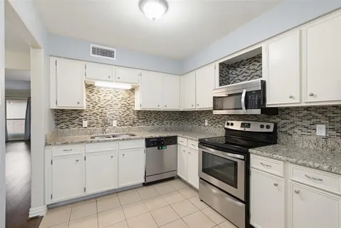 a kitchen with granite countertop white cabinets stainless steel appliances and a sink