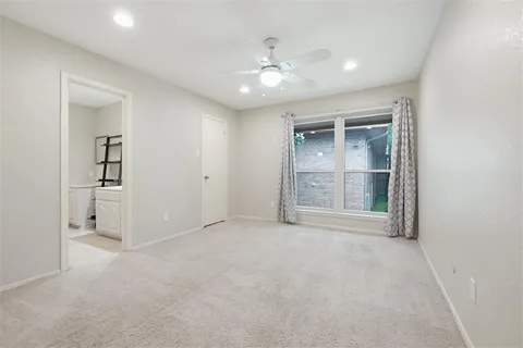 an empty room with chandelier fan and windows