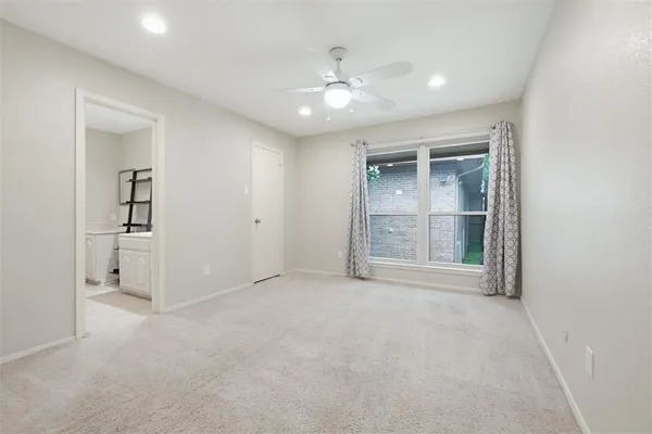 an empty room with chandelier fan and windows