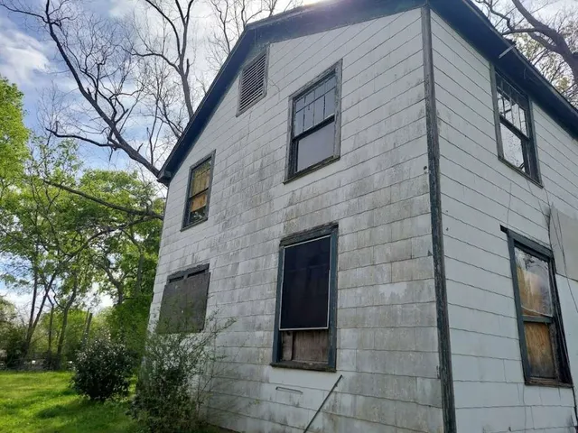 a brick building with a yard and large trees
