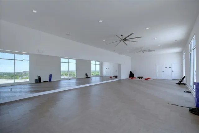 an empty room with windows and ceiling fan