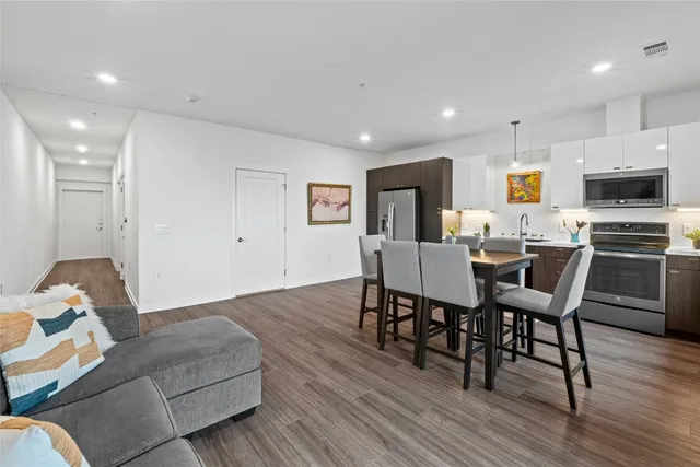a living room with furniture kitchen area and a wooden floor