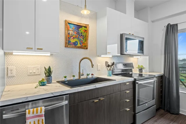 a kitchen with stainless steel appliances a sink a stove and cabinets