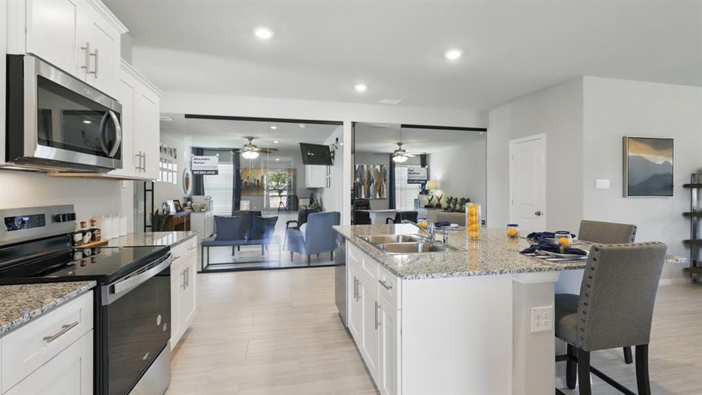 16413 Hudson Pr Way Justin, TX 76247 - Photo 4 of 36 a kitchen with stainless steel appliances granite countertop a sink dishwasher a stove with refrigerator a stove top oven and a dining table with wooden floor