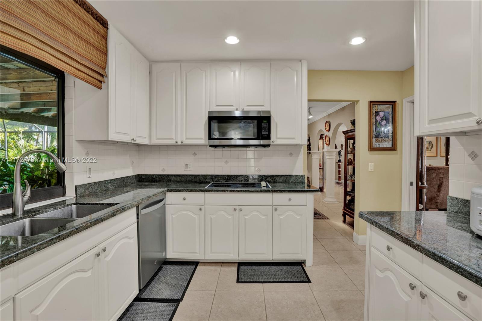 8695 Southwest 110th Street Miami, FL 33156 - Photo 45 of 54 a kitchen with granite countertop a sink and a stove top oven
