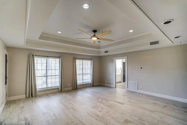 a view of an empty room with window and wooden floor