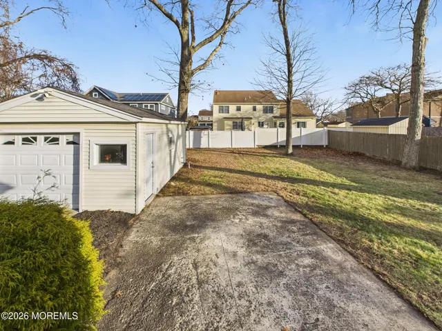 a view of a white house next to a yard with big trees