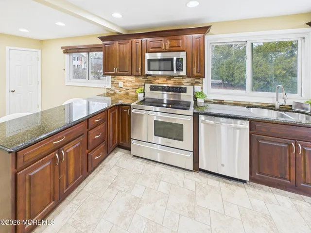 a kitchen with stainless steel appliances granite countertop a stove sink and cabinets