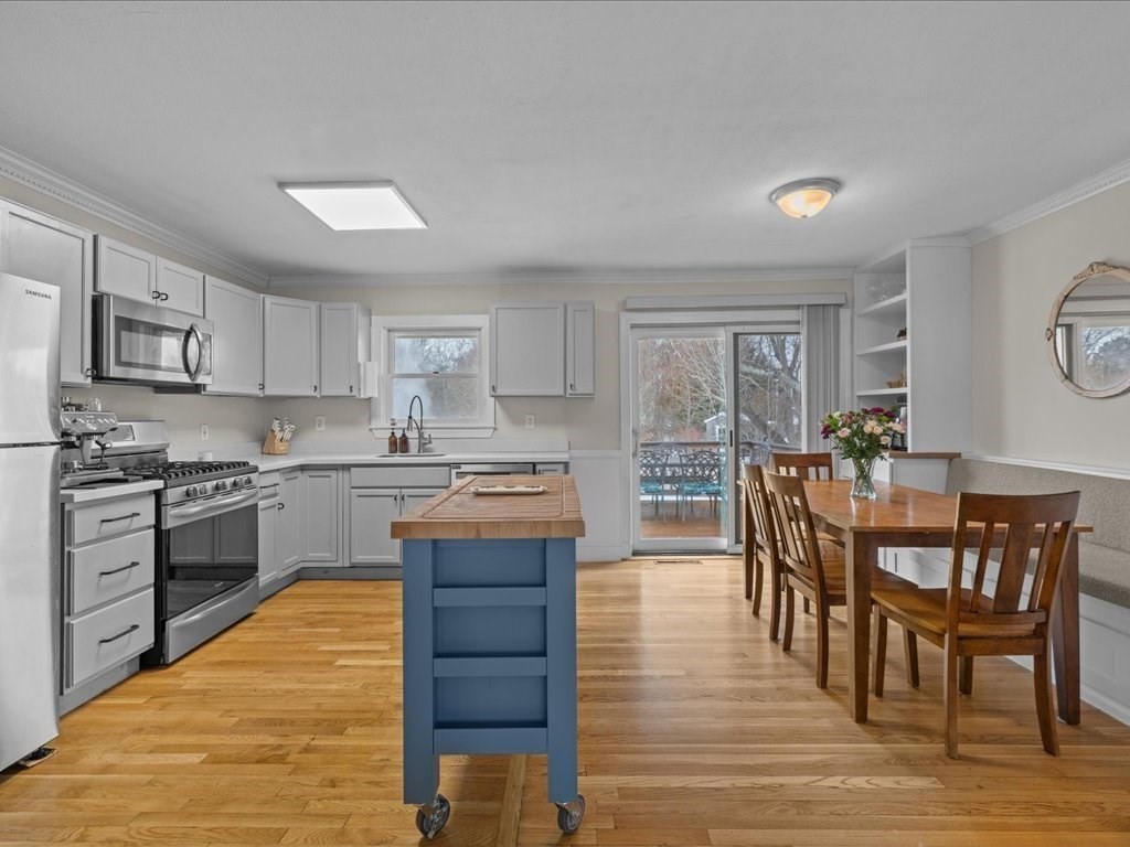 7 Pierce Road Marshfield, MA 02050 - Photo 10 of 34 a kitchen with stainless steel appliances granite countertop a stove top oven a sink a dining table and chairs with wooden floor