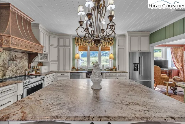 a kitchen with granite countertop a table chairs stainless steel appliances and windows