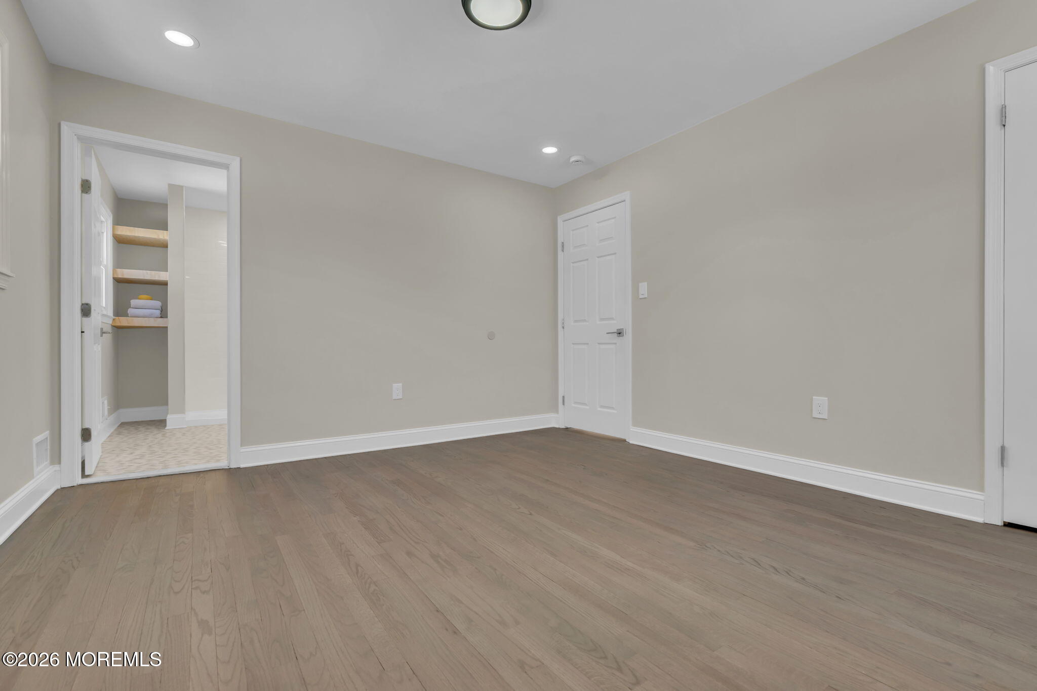a view of an empty room with wooden floor and closet