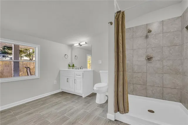 a bathroom with a granite countertop sink a toilet a mirror and shower