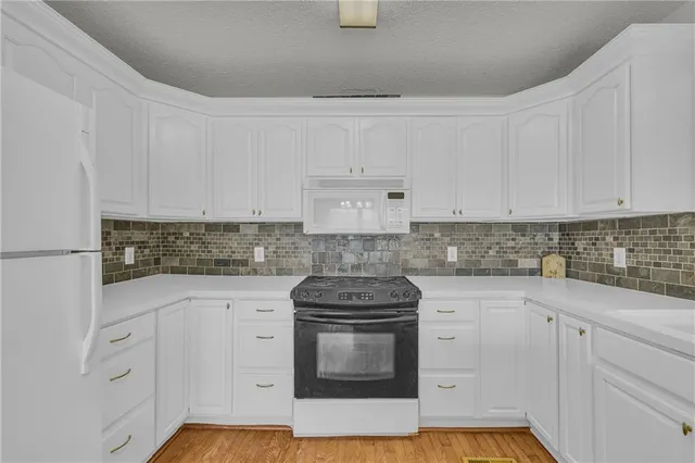 a kitchen with granite countertop white cabinets and a stove with wooden floor