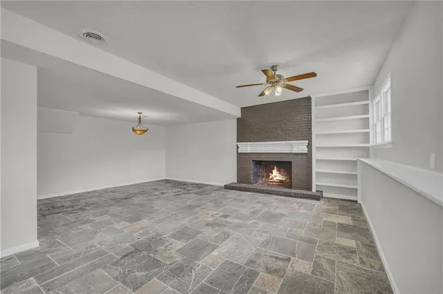 a view of an empty room with a fireplace and a chandelier fan