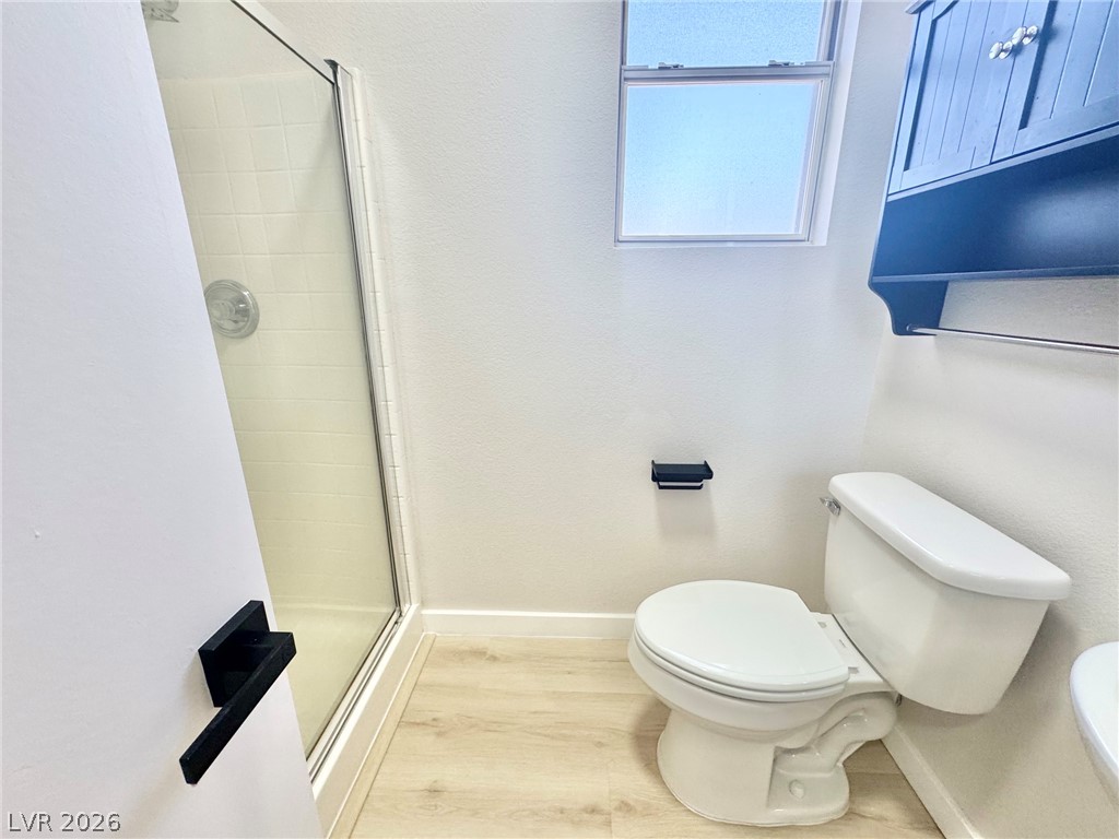 7340 Ridge Star Court Las Vegas, NV 89131 - Photo 15 of 22 A well-lit bathroom features light wood-look flooring and a functional shower with a clear glass enclosure.