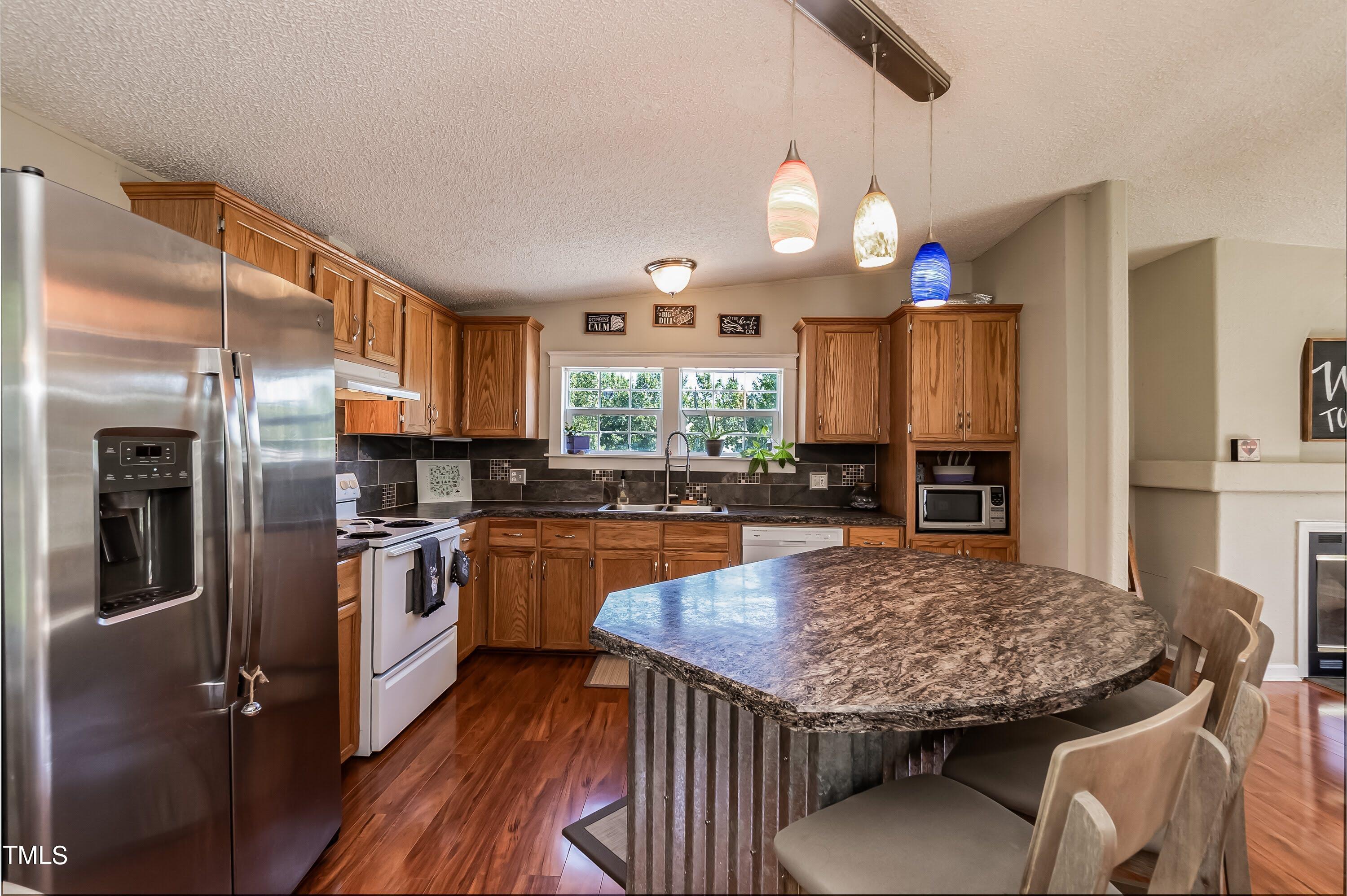 552 Locks Lane Rougemont, NC 27572 - Photo 17 of 45 a kitchen with stainless steel appliances granite countertop a kitchen island hardwood floor sink stove dining table and chairs