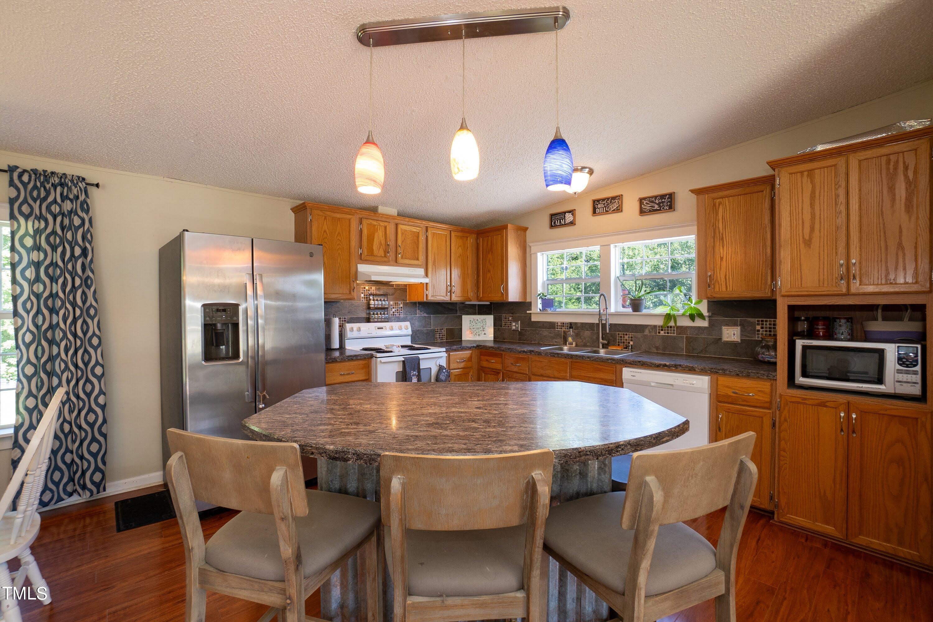 552 Locks Lane Rougemont, NC 27572 - Photo 18 of 45 a kitchen with granite countertop a table chairs stove microwave and cabinets