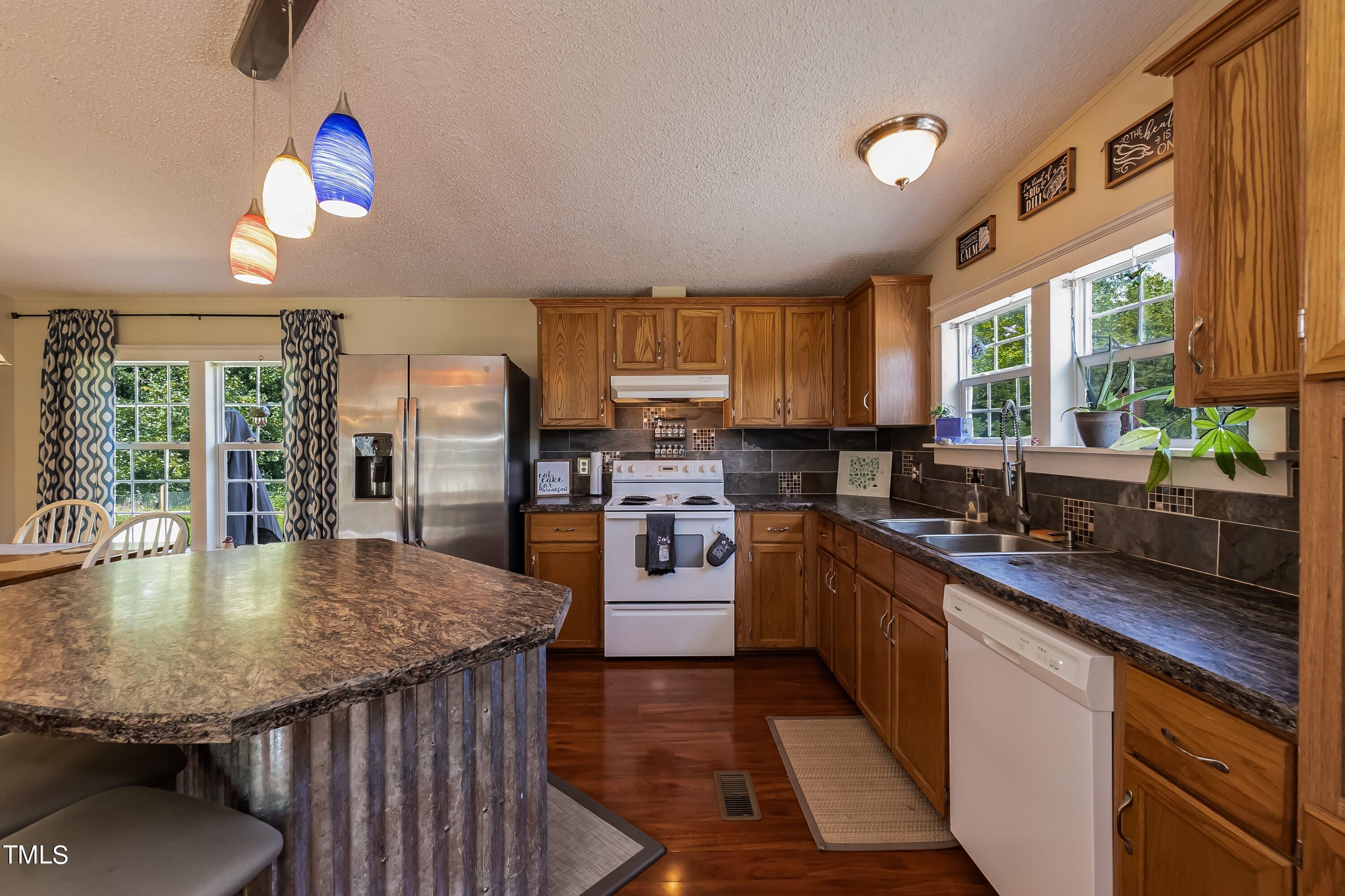 552 Locks Lane Rougemont, NC 27572 - Photo 19 of 45 a kitchen with stainless steel appliances granite countertop a sink refrigerator dining table and chairs