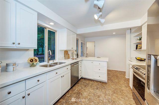 a kitchen with white cabinets and sink