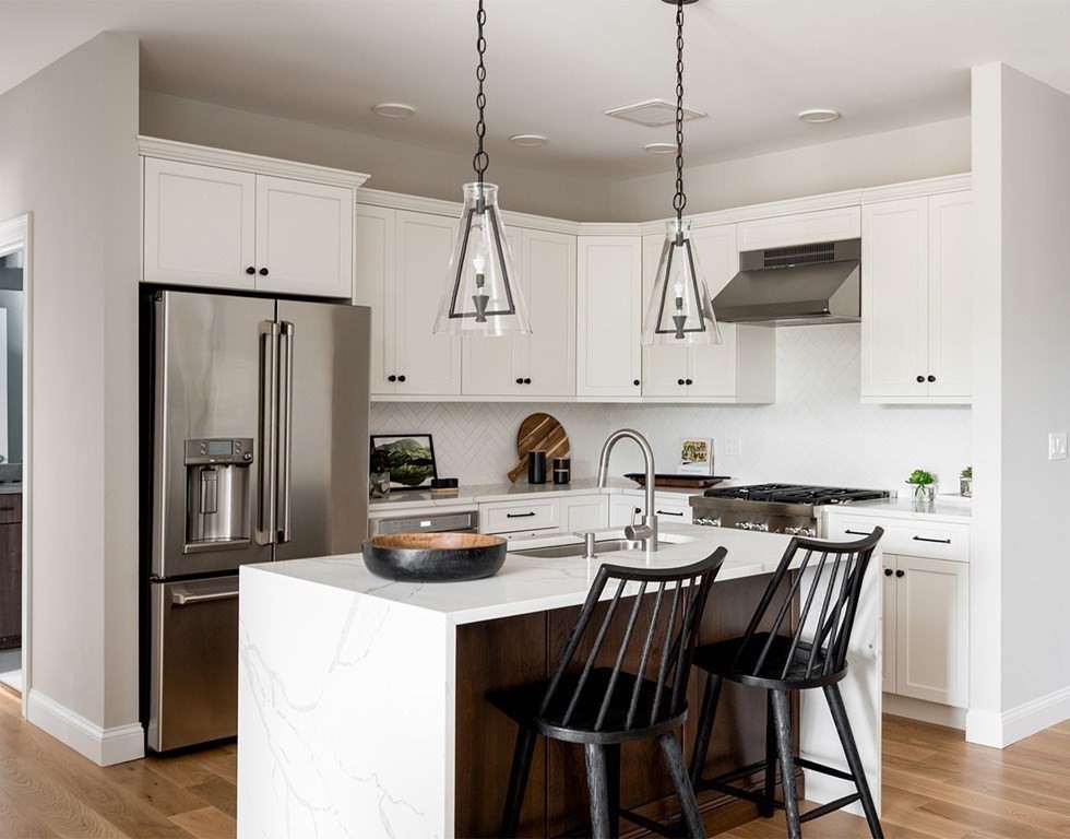 50 Coppersmith Way, Unit 107 Canton, MA 02021 - Photo 13 of 42 a kitchen with stainless steel appliances granite countertop a stove a refrigerator a sink a dining table and chairs with wooden floor