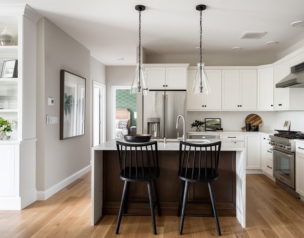 50 Coppersmith Way, Unit 107 Canton, MA 02021 - Photo 17 of 42 a kitchen with stainless steel appliances kitchen island granite countertop a dining table chairs and white cabinets