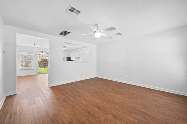 a view of an empty room with window and wooden floor