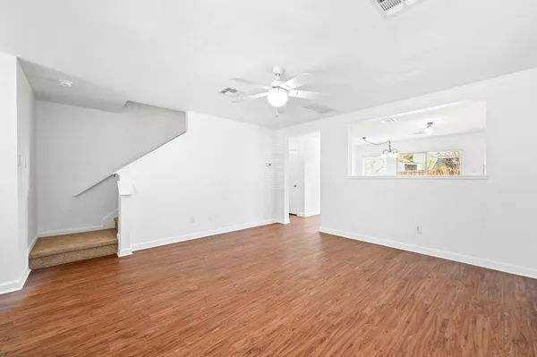 an empty room with wooden floor and a ceiling fan