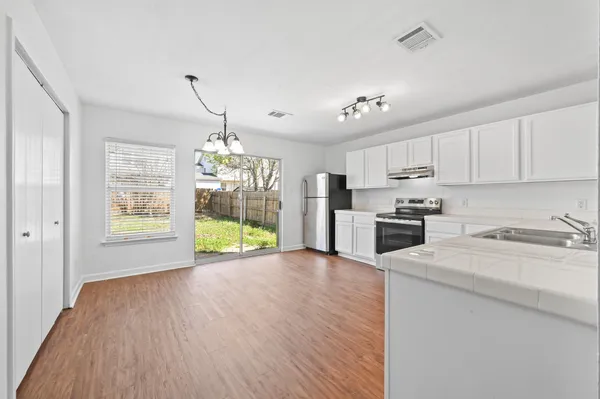 a kitchen with stainless steel appliances granite countertop a stove top oven a sink dishwasher and a refrigerator with wooden floor