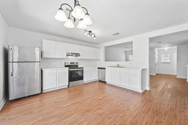 a kitchen with a white cabinets stainless steel appliances and wooden floor