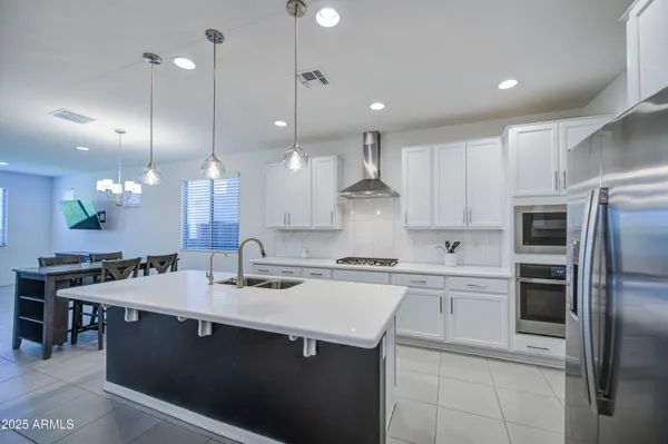a kitchen with a sink a center island stainless steel appliances and cabinets