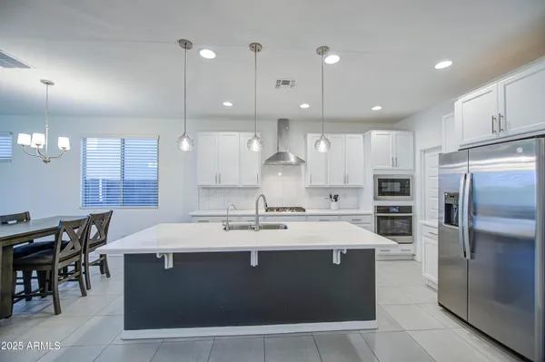 a large kitchen with stainless steel appliances a large counter top a sink refrigerator and cabinets