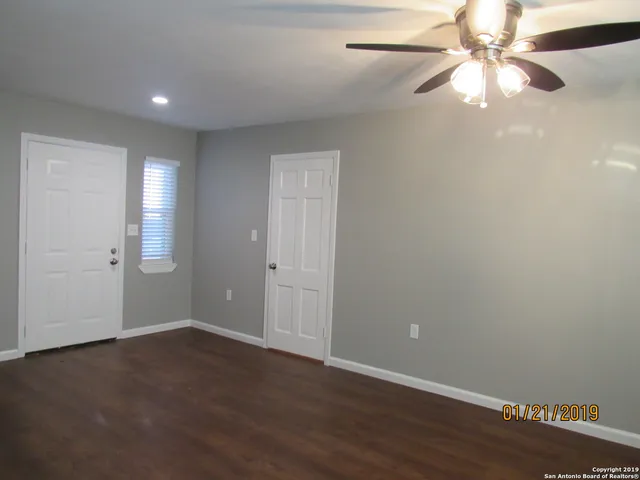 a view of an empty room with window and wooden floor