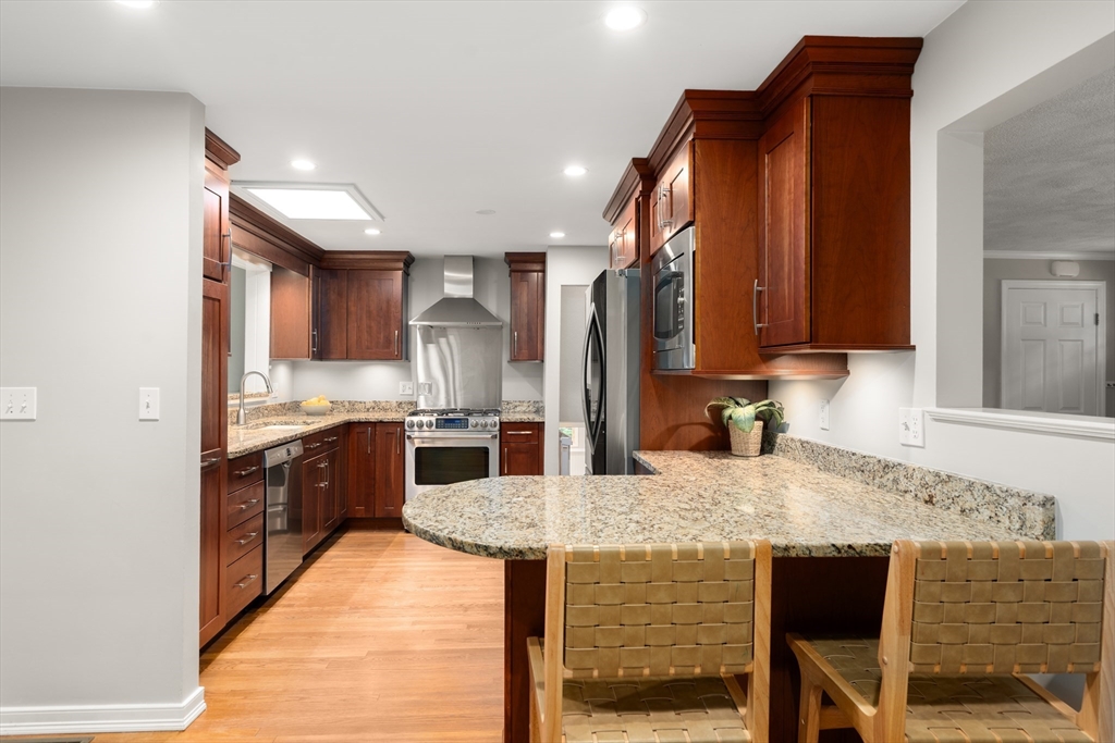 73 Willow Road Sudbury, MA 01776 - Photo 12 of 41 a kitchen with kitchen island granite countertop a sink and wooden cabinets