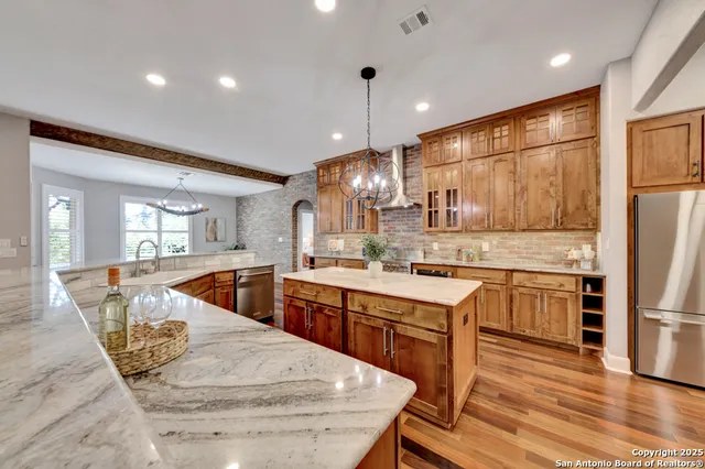 a kitchen with stainless steel appliances granite countertop a sink a stove and a wooden floors