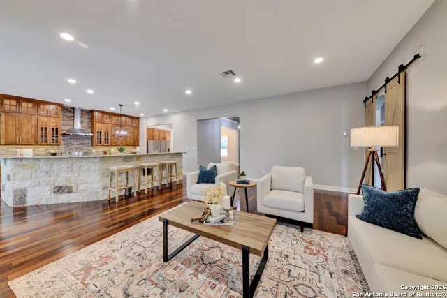 a kitchen with stainless steel appliances granite countertop a stove top oven a refrigerator a sink and a dining table with wooden floor