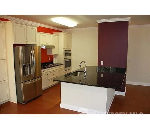 a kitchen with stainless steel appliances kitchen island granite countertop a refrigerator and a sink