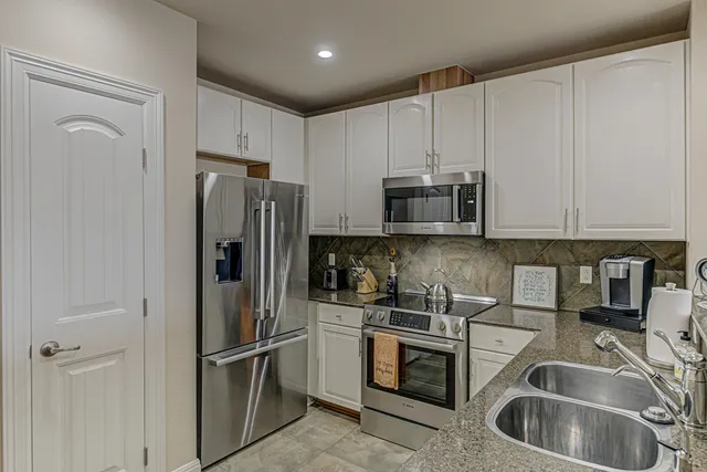 a kitchen with stainless steel appliances granite countertop a refrigerator and a sink