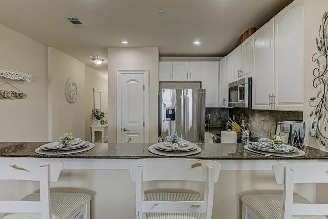 a kitchen with stainless steel appliances kitchen island granite countertop a refrigerator and cabinets