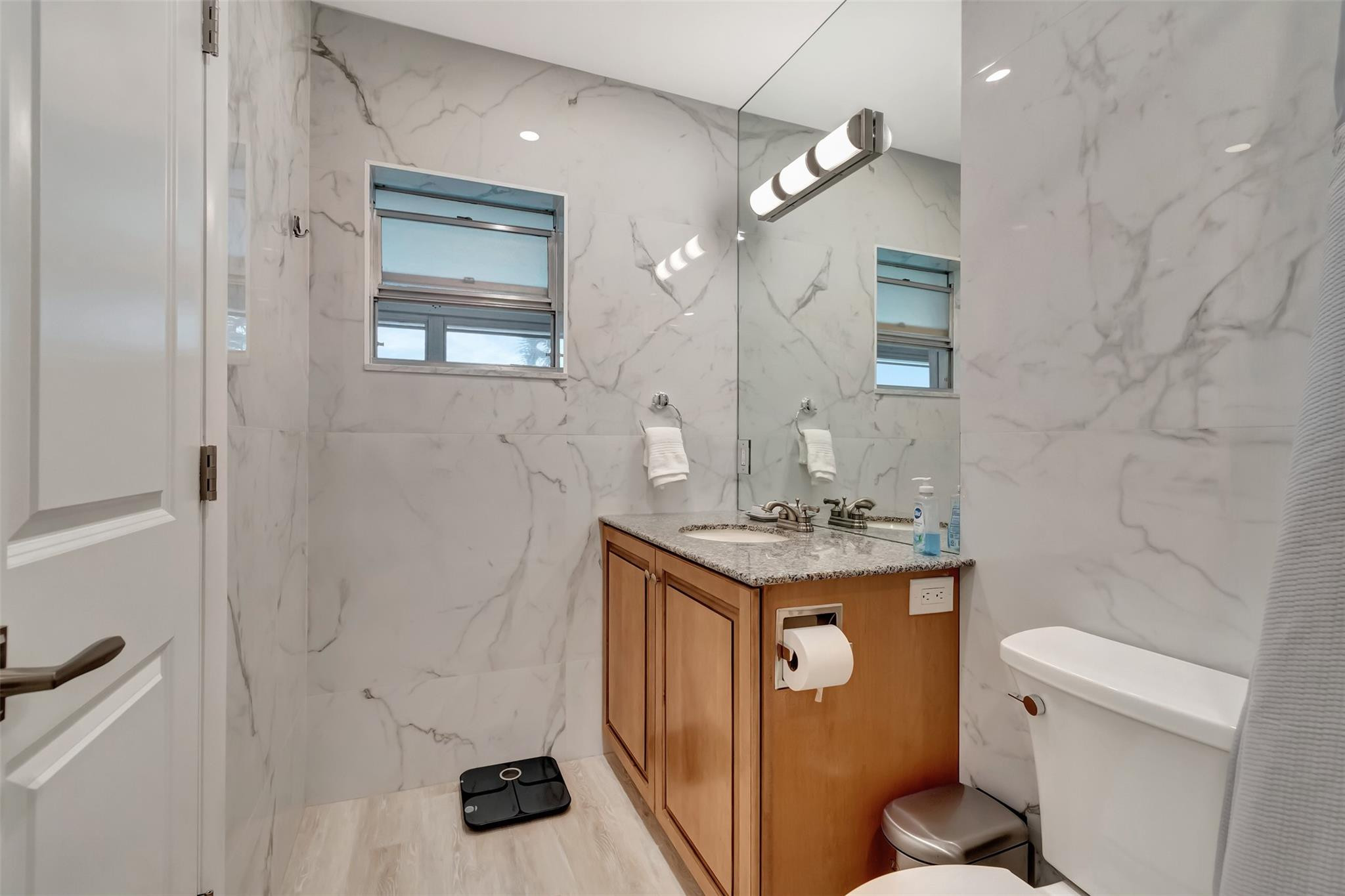 5520 North Ocean Boulevard, Unit 210 Ocean Ridge, FL 33435 - Photo 22 of 40 a bathroom with a granite countertop sink a toilet and a mirror