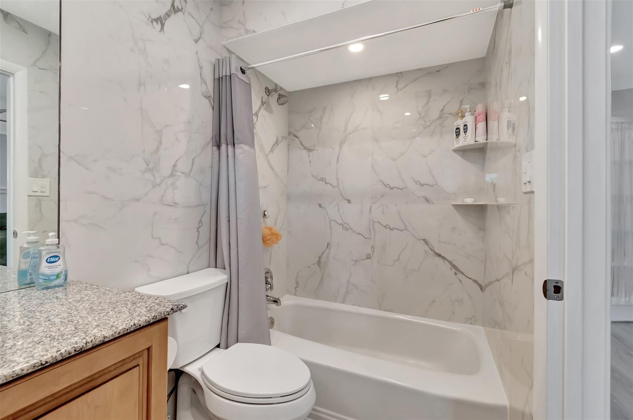 5520 North Ocean Boulevard, Unit 210 Ocean Ridge, FL 33435 - Photo 23 of 40 a bathroom with a granite countertop sink a toilet and shower