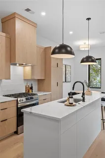 a kitchen with stainless steel appliances a stove a sink dishwasher and a refrigerator with wooden floor