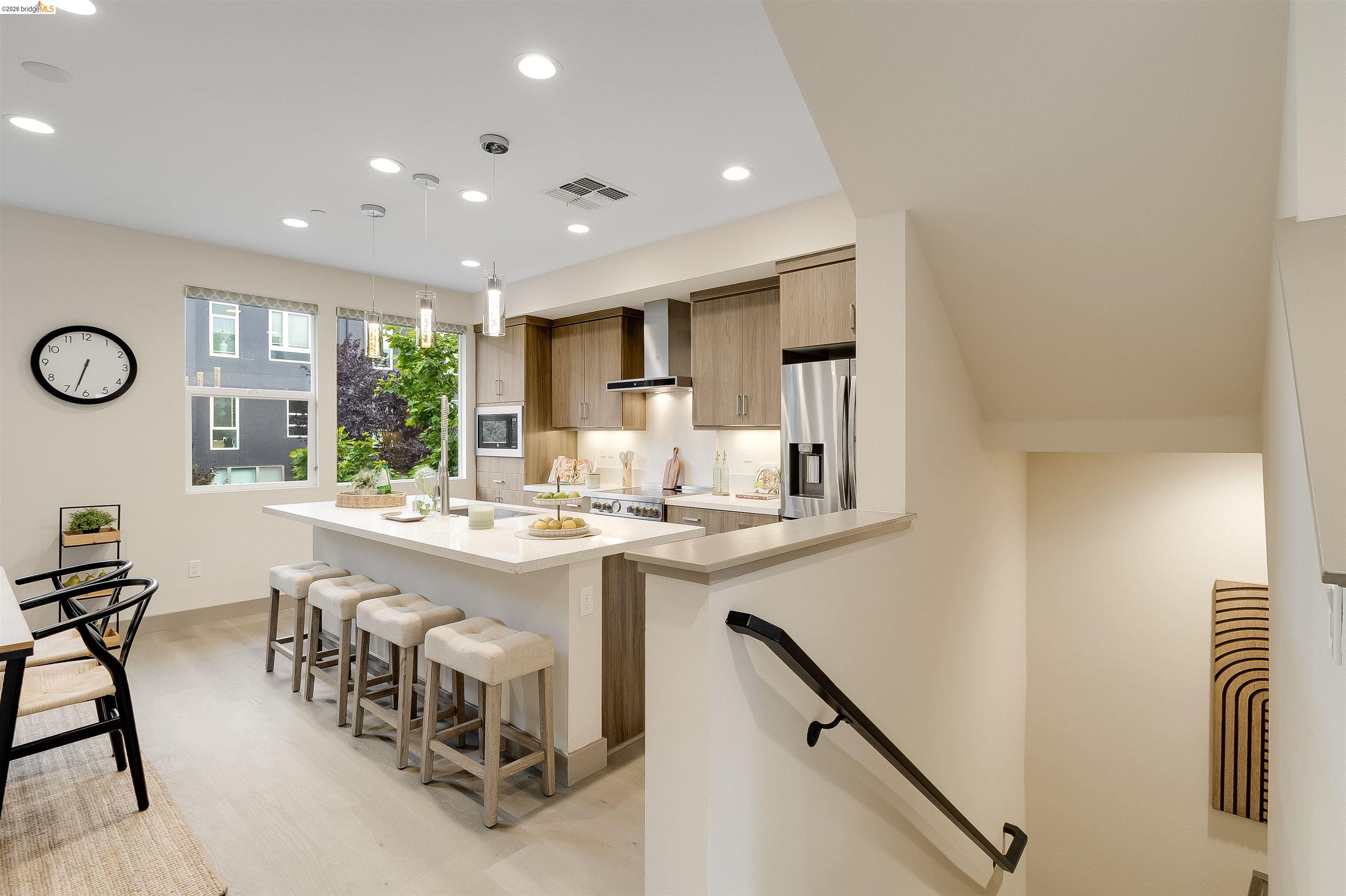 1357 Pullman Way Oakland, CA 94607 - Photo 9 of 37 Modern kitchen with light wood-finish cabinetry, stainless steel appliances, and a central island with countertop seating
