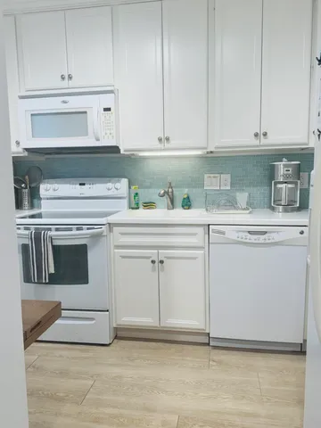 a kitchen with white cabinets and white appliances