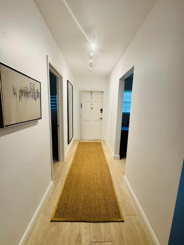 a view of a hallway with wooden floor and closet