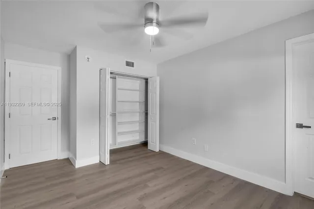an empty room with wooden floor closet and windows
