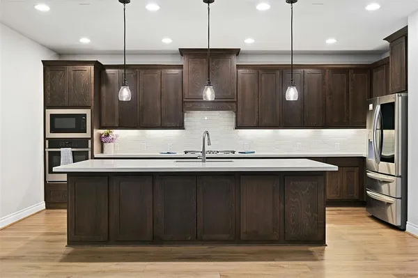 a large kitchen with a large counter top a sink stainless steel appliances and cabinets