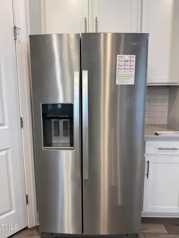 a metallic refrigerator freezer sitting inside of a kitchen