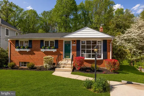a backyard of a house with table and chairs potted plants and large tree