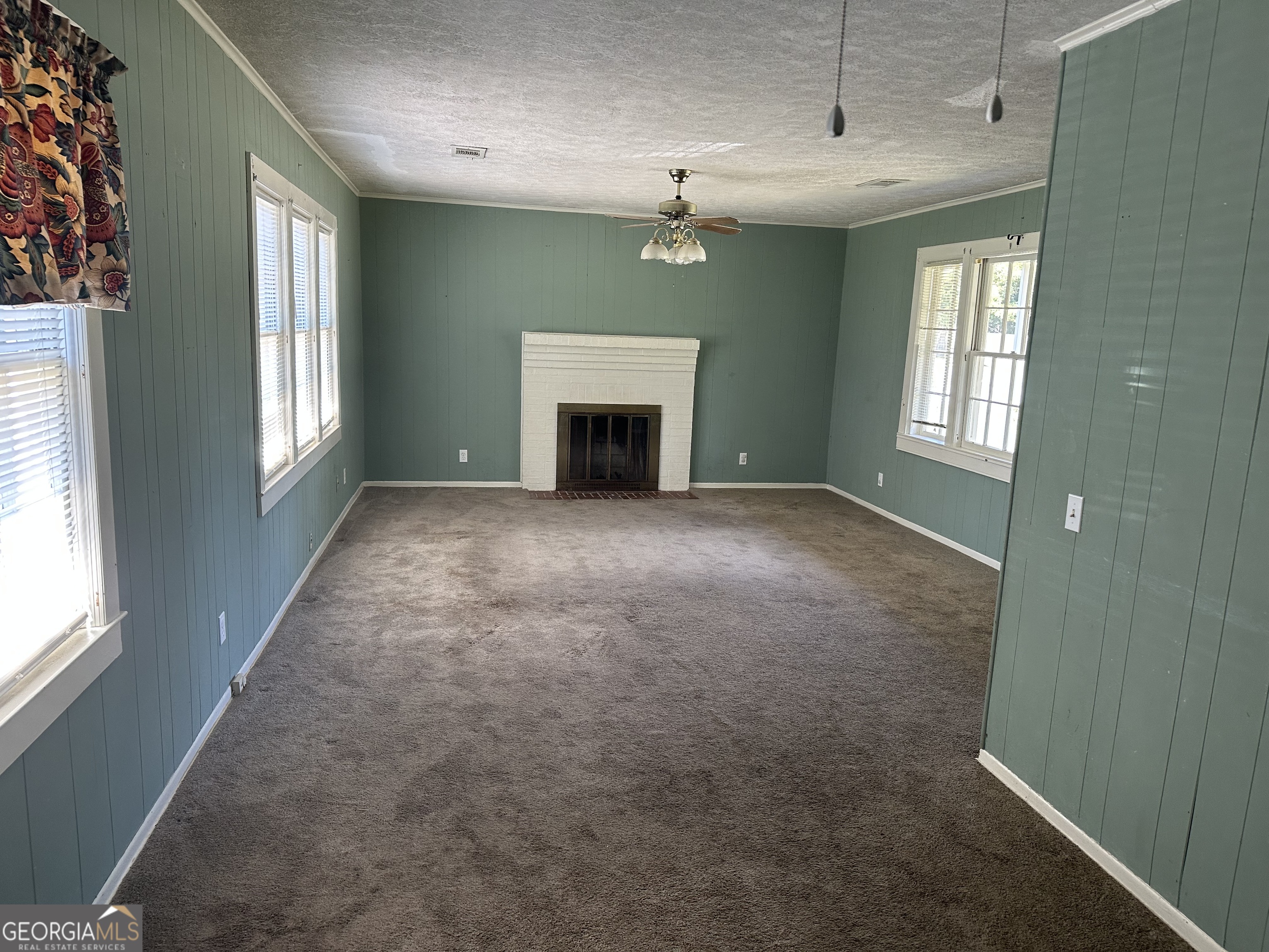 202 Geneva Street Dublin, GA 31021 - Photo 11 of 14 an empty room with windows fireplace and fans
