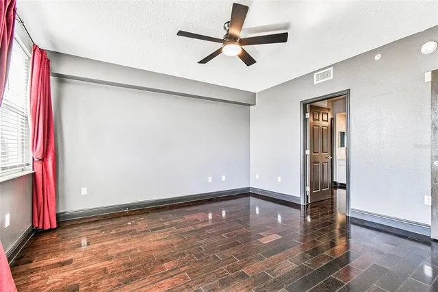 a view of an empty room with a window and wooden floor